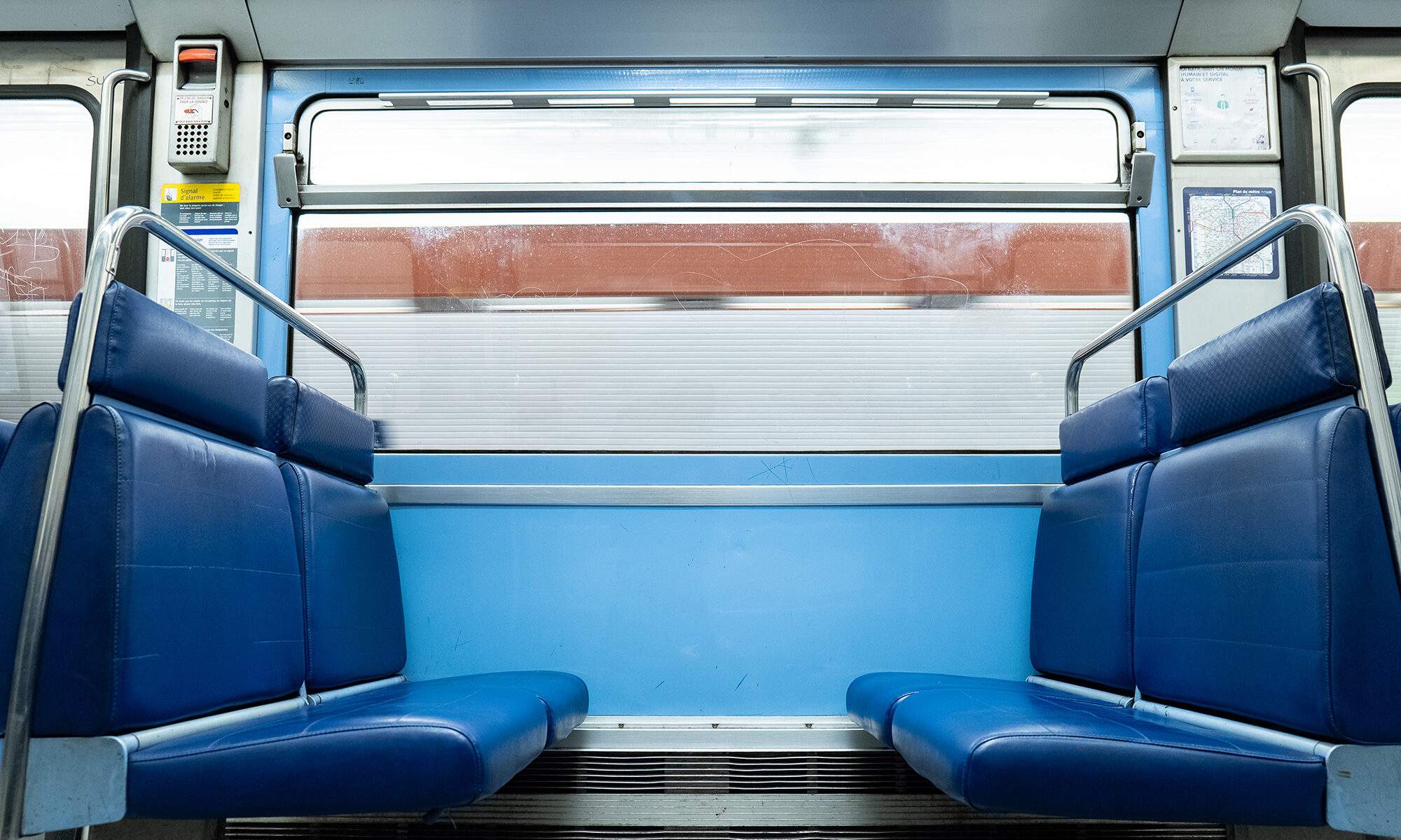 Un carré de quatre places vides dans une rame de métro bleue en mouvement